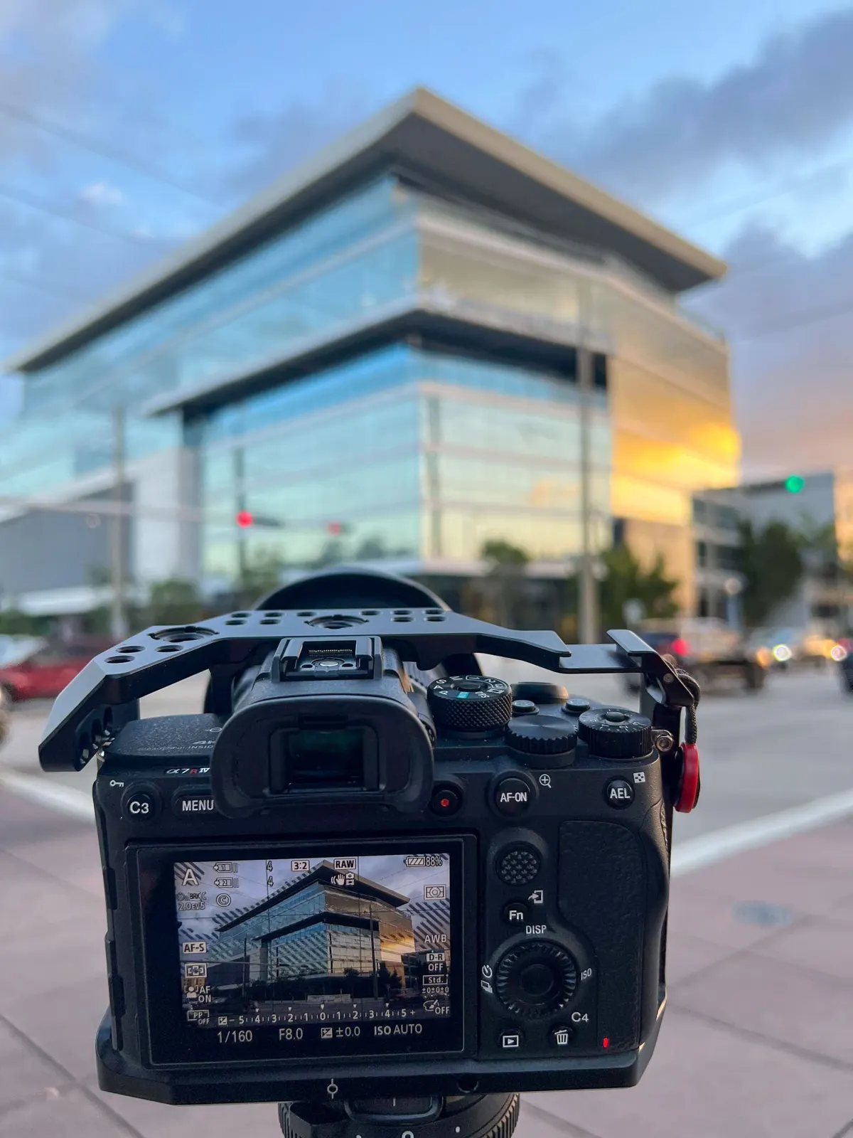 A camera framing an office tower at sunset