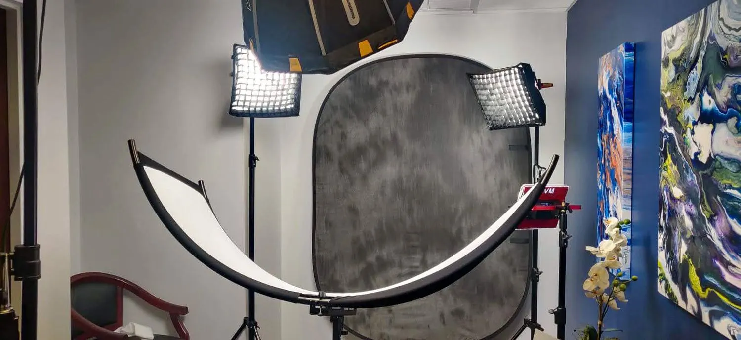 A grey backdrop with a reflector and two LED panels set up in an office