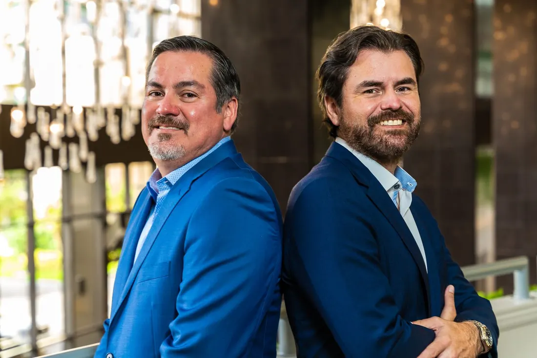 Two business partners standing back to back in an office lobby