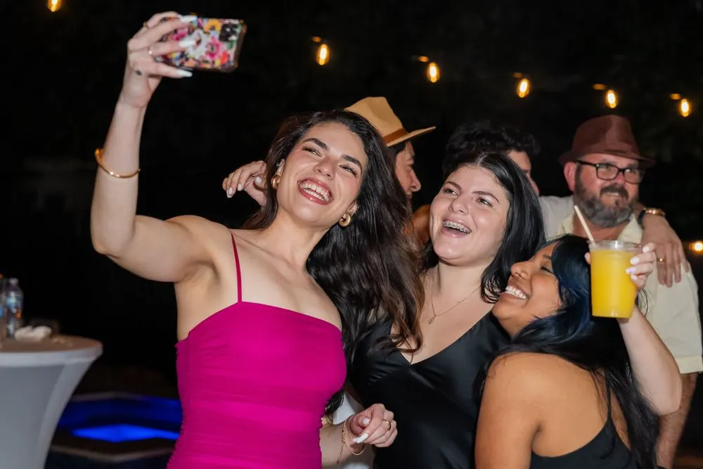 A group of friends laughing together for a selfie at a client's wedding