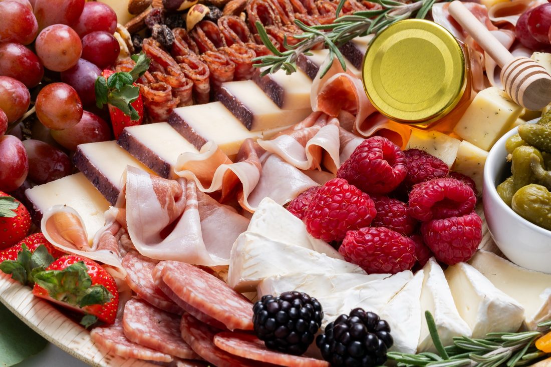 A charcuterie board with grapes, cheeses, cured meats and berries
