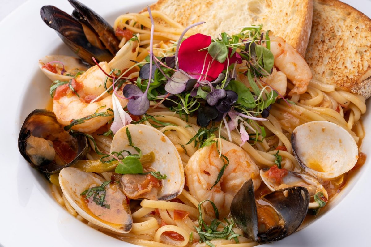 Seafood linguine with clams, mussels and shrimp, topped with microgreens