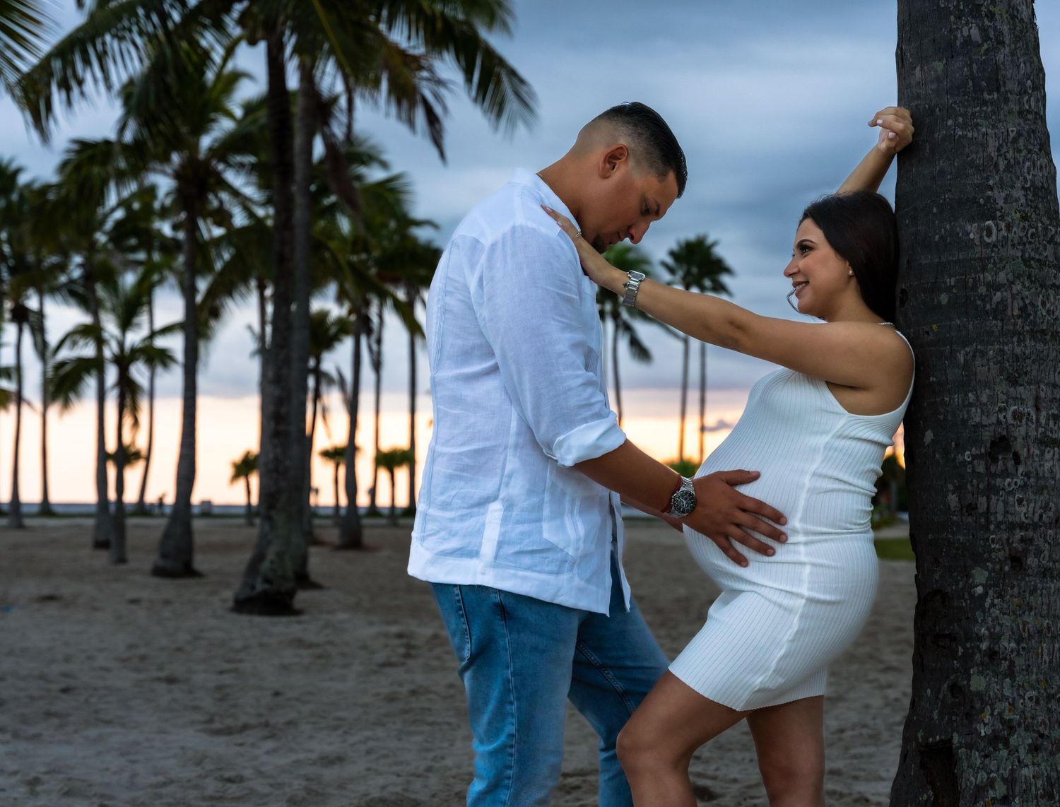 Expecting couple smiling together under mangrove trees