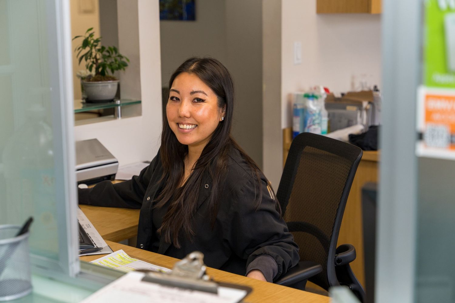 Receptionist smiling at the camera from a front desk window