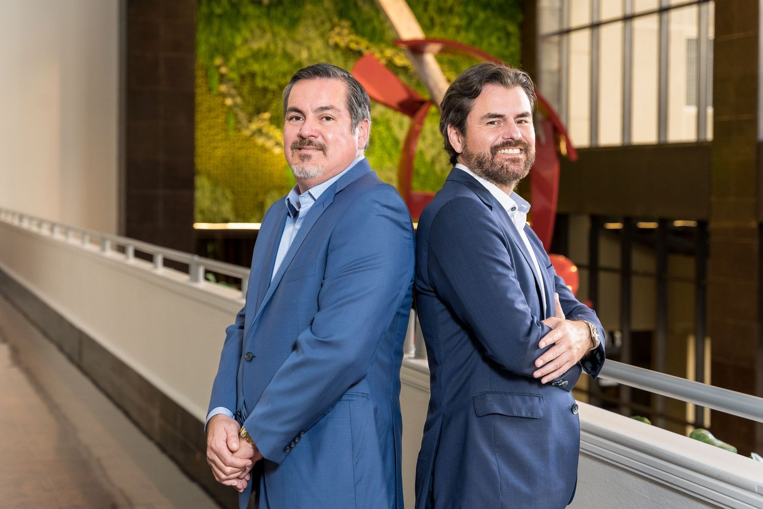 Two business partners in suits standing in a marble office lobby