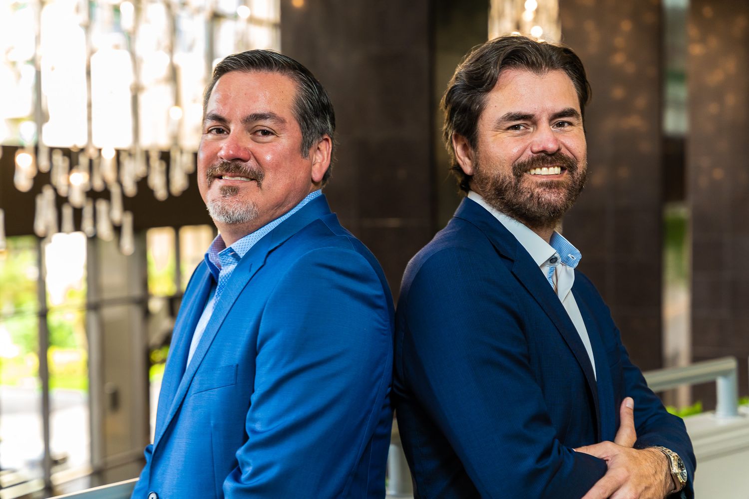Two colleagues laughing together in a bright office hallway