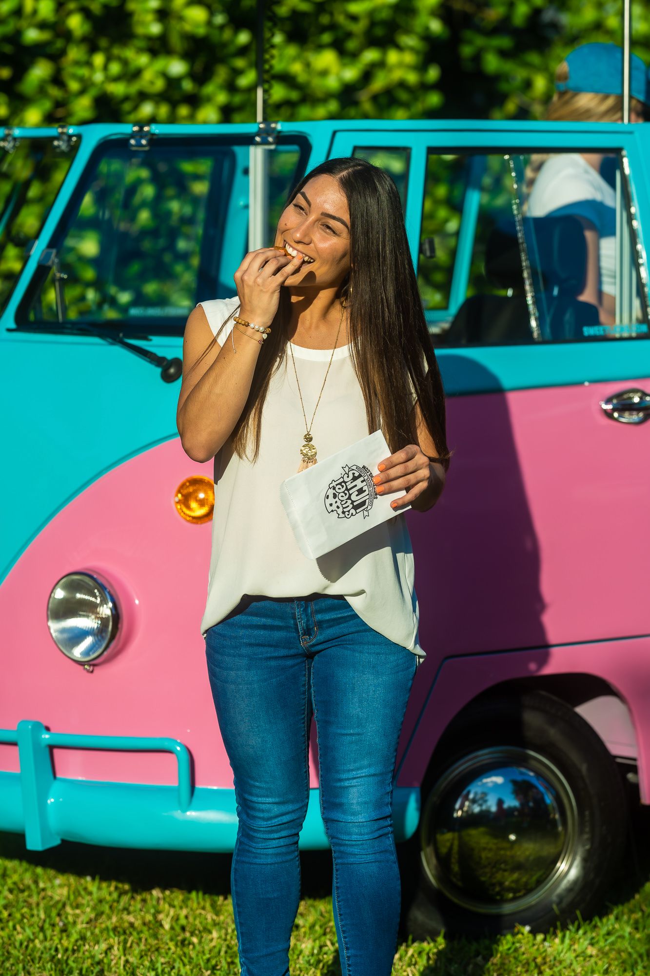 Customer enjoying a treat in front of a branded pink and teal food truck