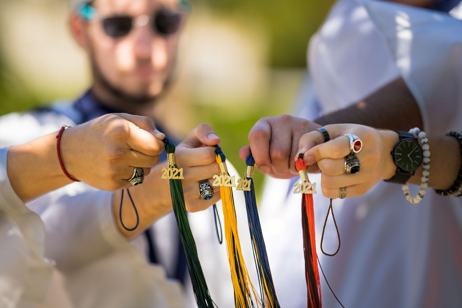 Close-up of hands tying on graduation cords together before the ceremony