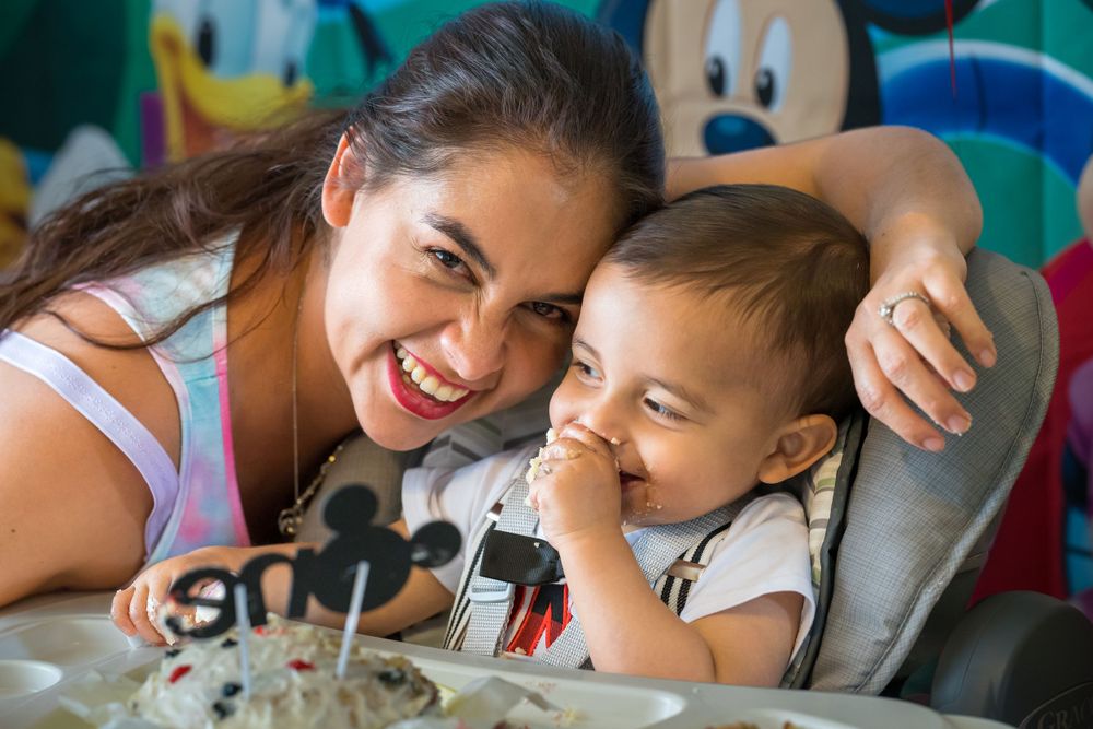 Mother hugging her toddler at a Mickey Mouse themed birthday celebration