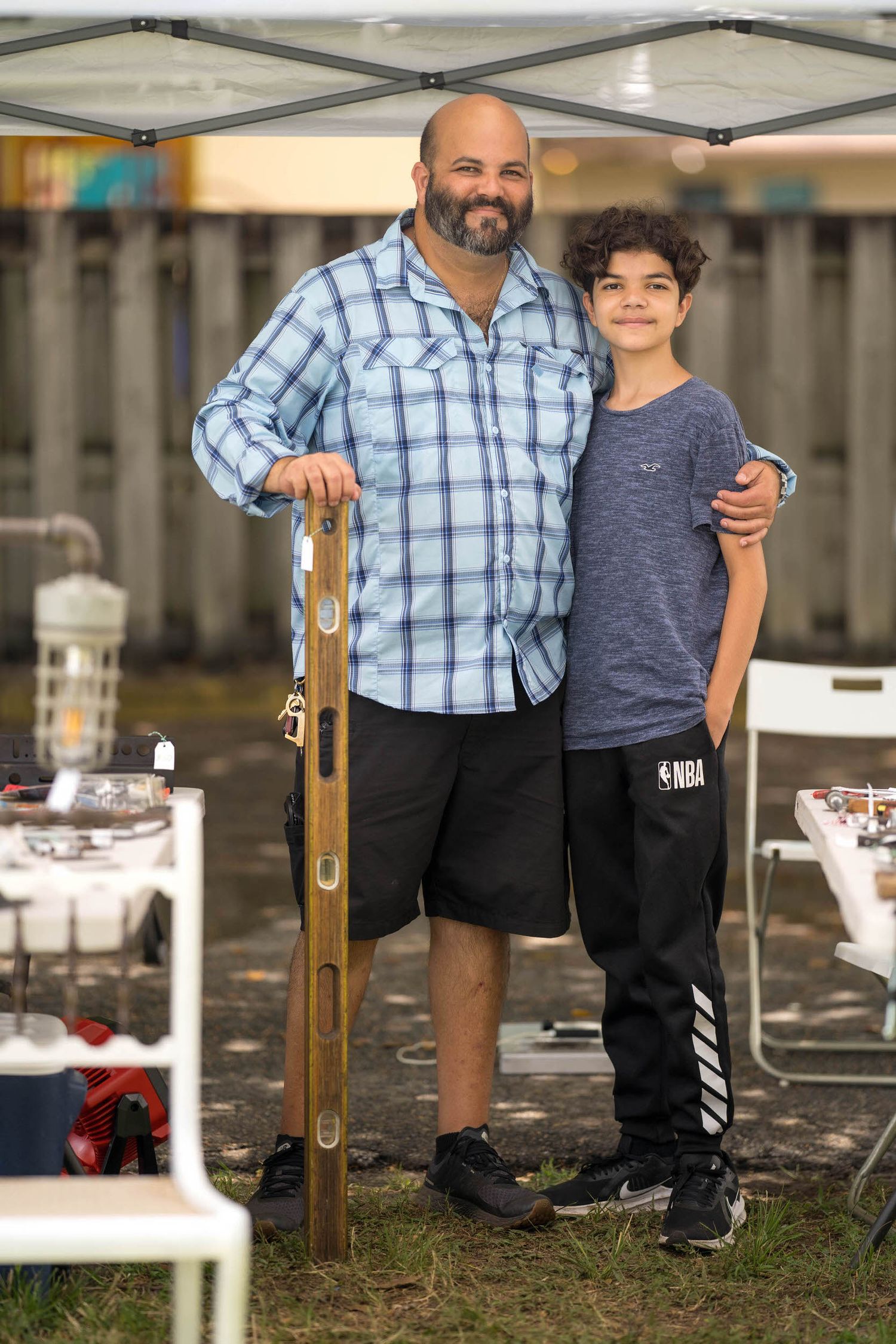 Father with his arm around his preteen son at an outdoor community event