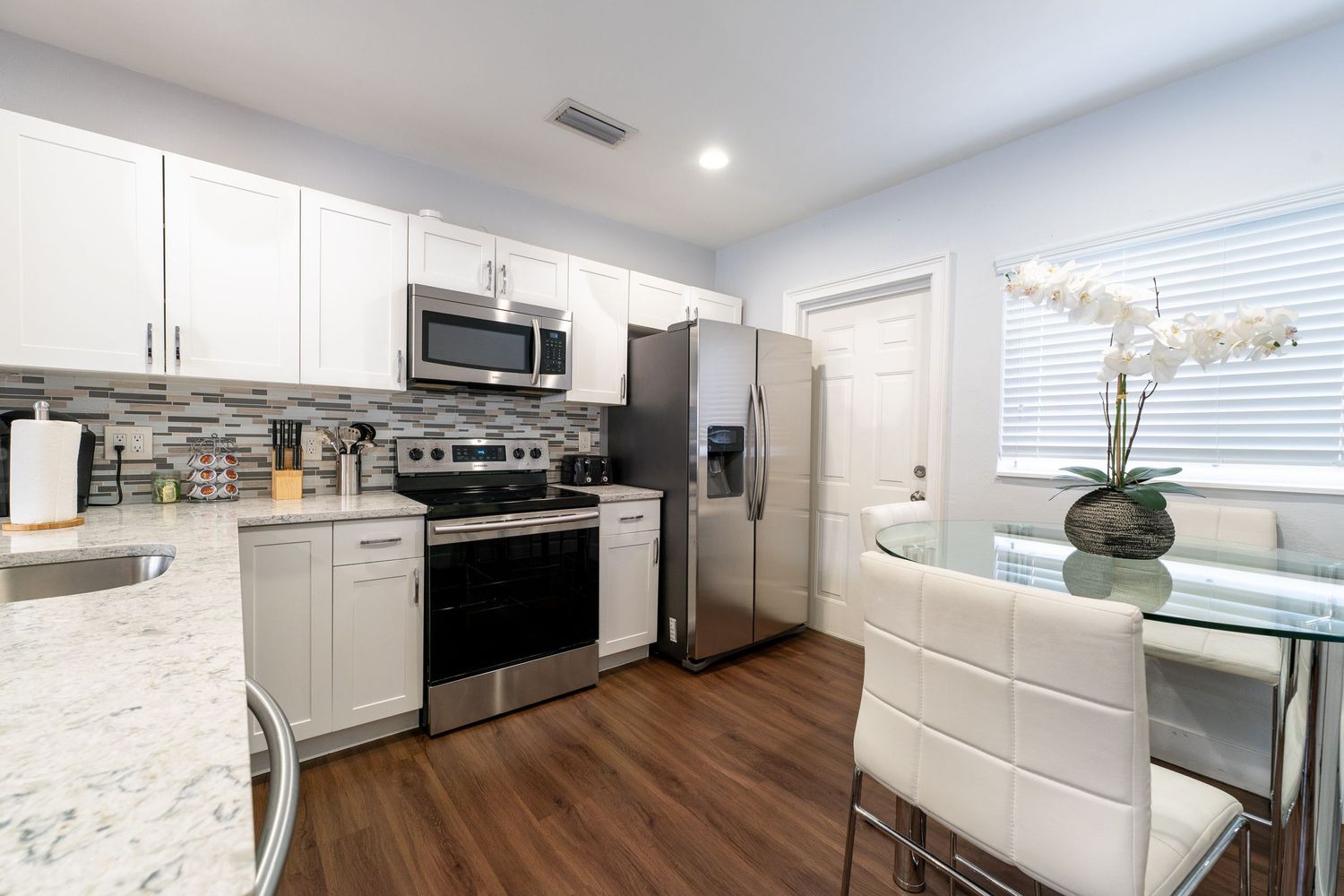 Modern kitchen with white cabinetry, granite counters, and stainless steel appliances