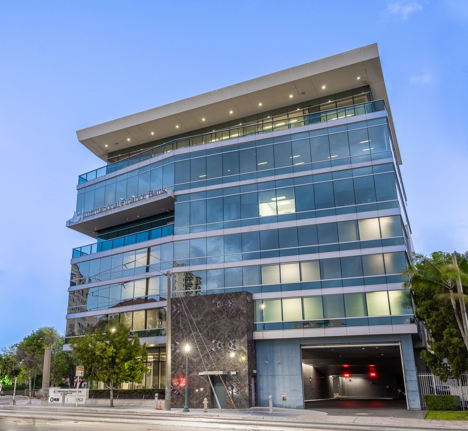 Modern glass office tower photographed at dusk with illuminated windows