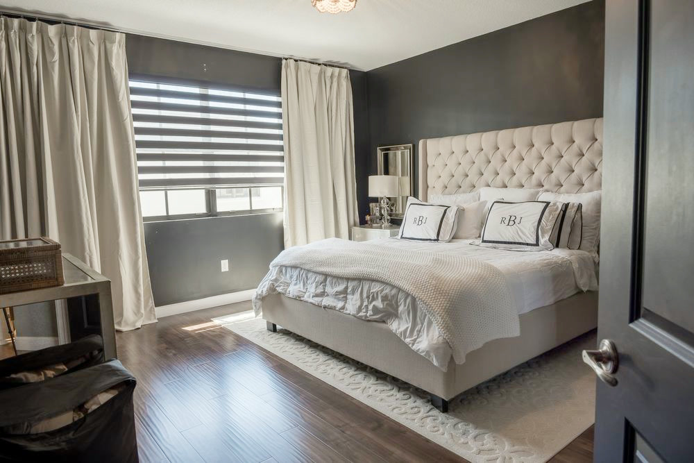 Habitación principal con una pared de acento oscura y un cabecero tapizado capitoné
