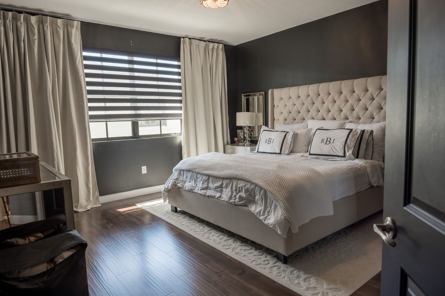 Primary bedroom with a dark accent wall and a tufted upholstered headboard