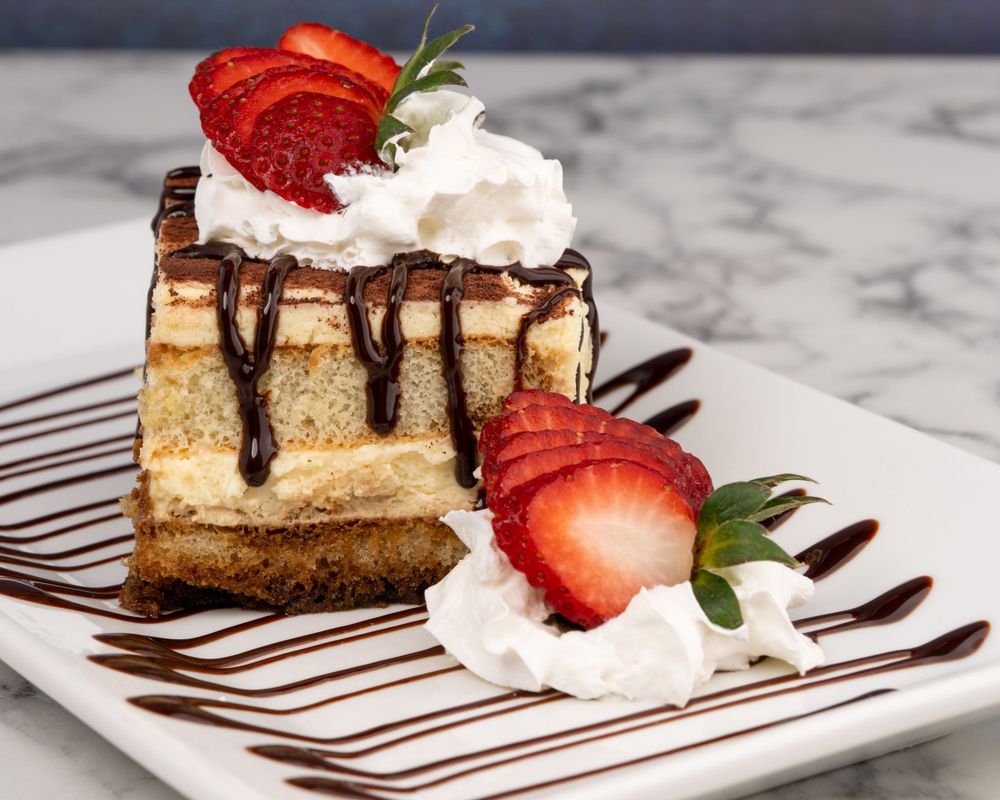 Porción de cheesecake con fresas y chorritos de chocolate