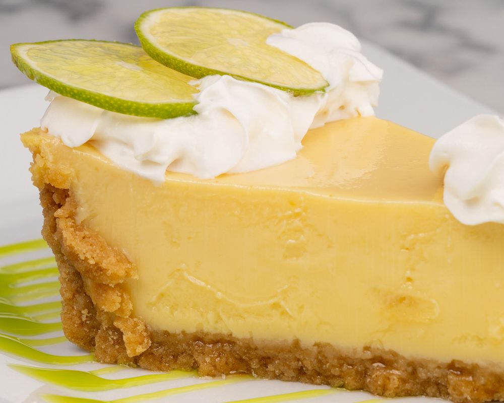 Porción de key lime pie con crema batida y limón