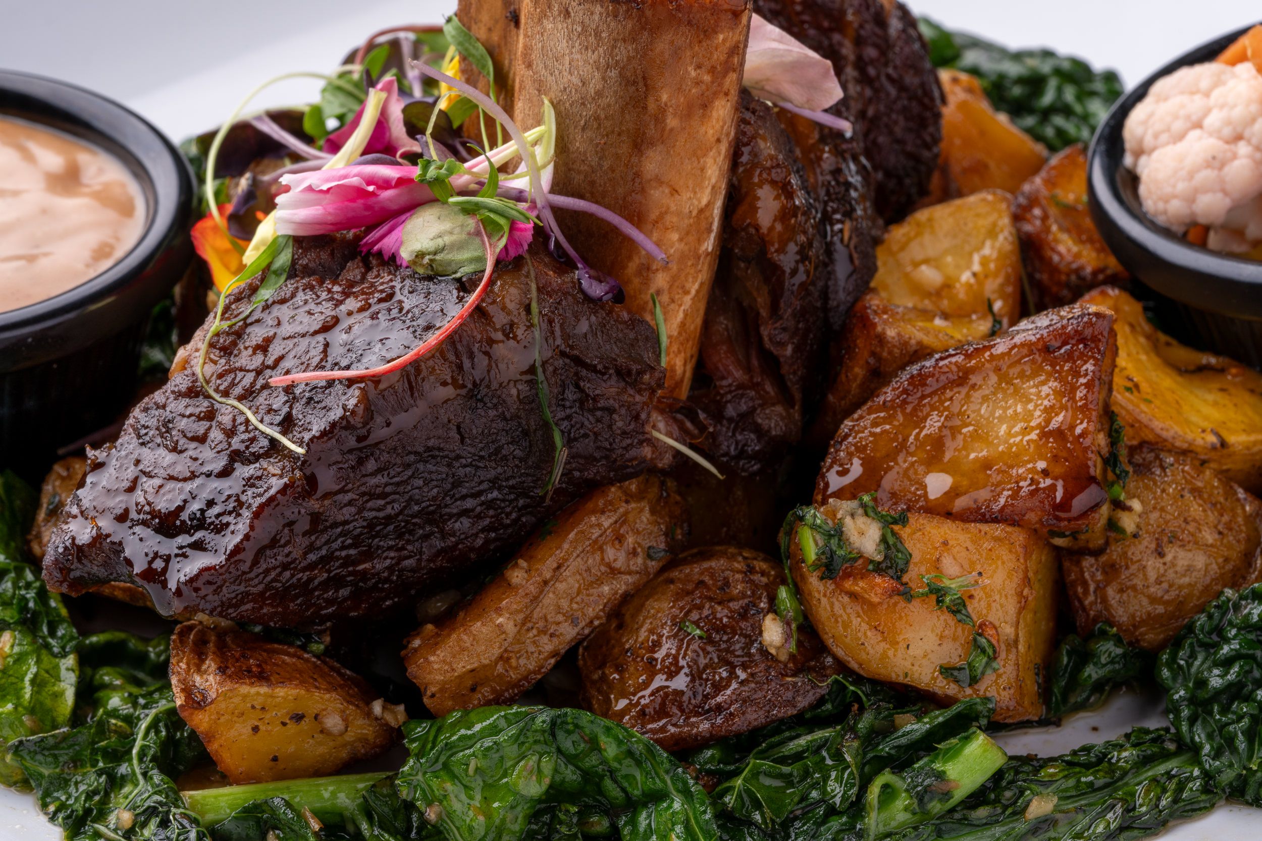 Braised short rib plated with roasted potatoes and greens