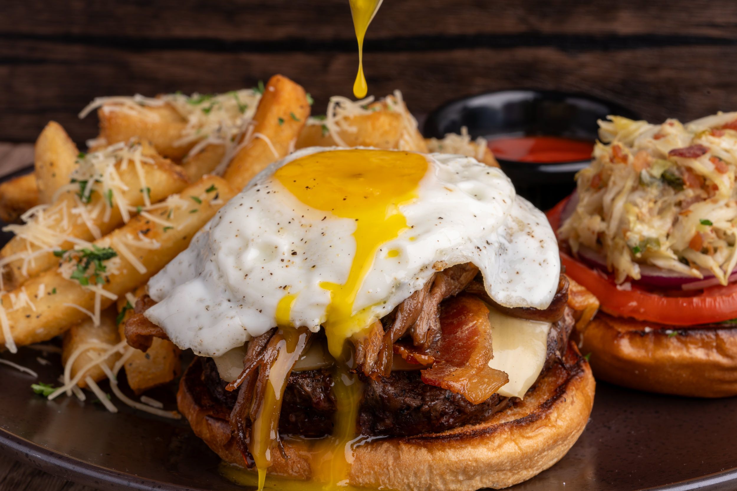 Una hamburguesa con un huevo frito encima y la yema derramándose