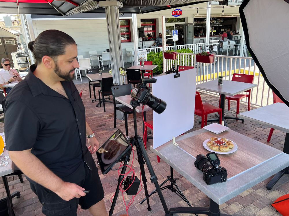 Nuestro fotógrafo revisando una cámara montada sobre un plato servido en la terraza de un restaurante