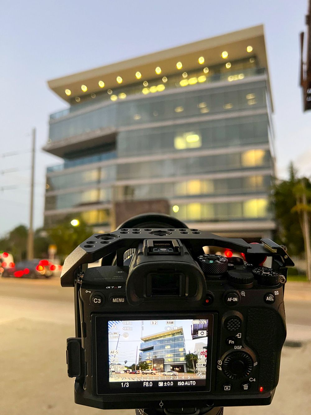 Vista en vivo de la cámara con la fachada iluminada de un edificio de oficinas al atardecer