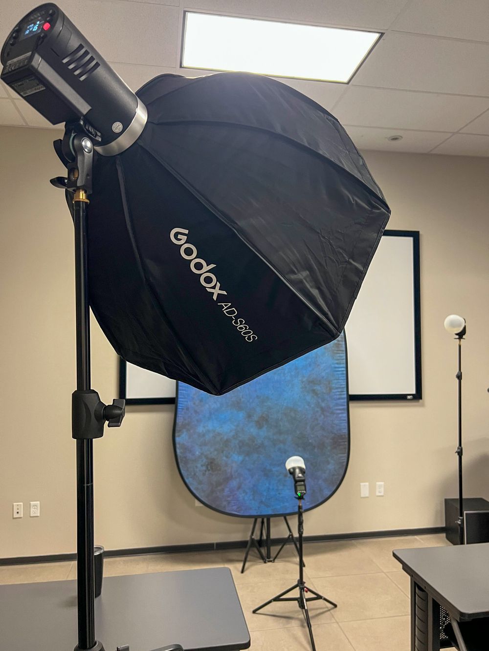 Una softbox y un fondo portátil azul montados en una oficina para una entrevista