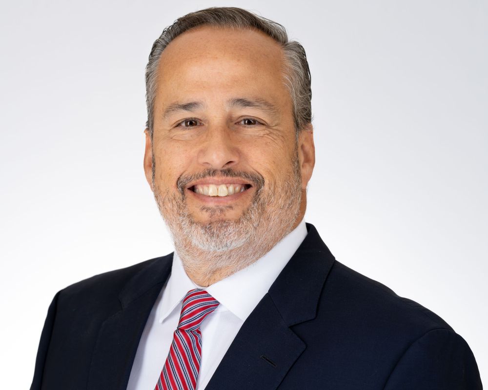 Retrato de estudio sobre fondo blanco, hombre sonriente con traje azul marino y corbata de rayas
