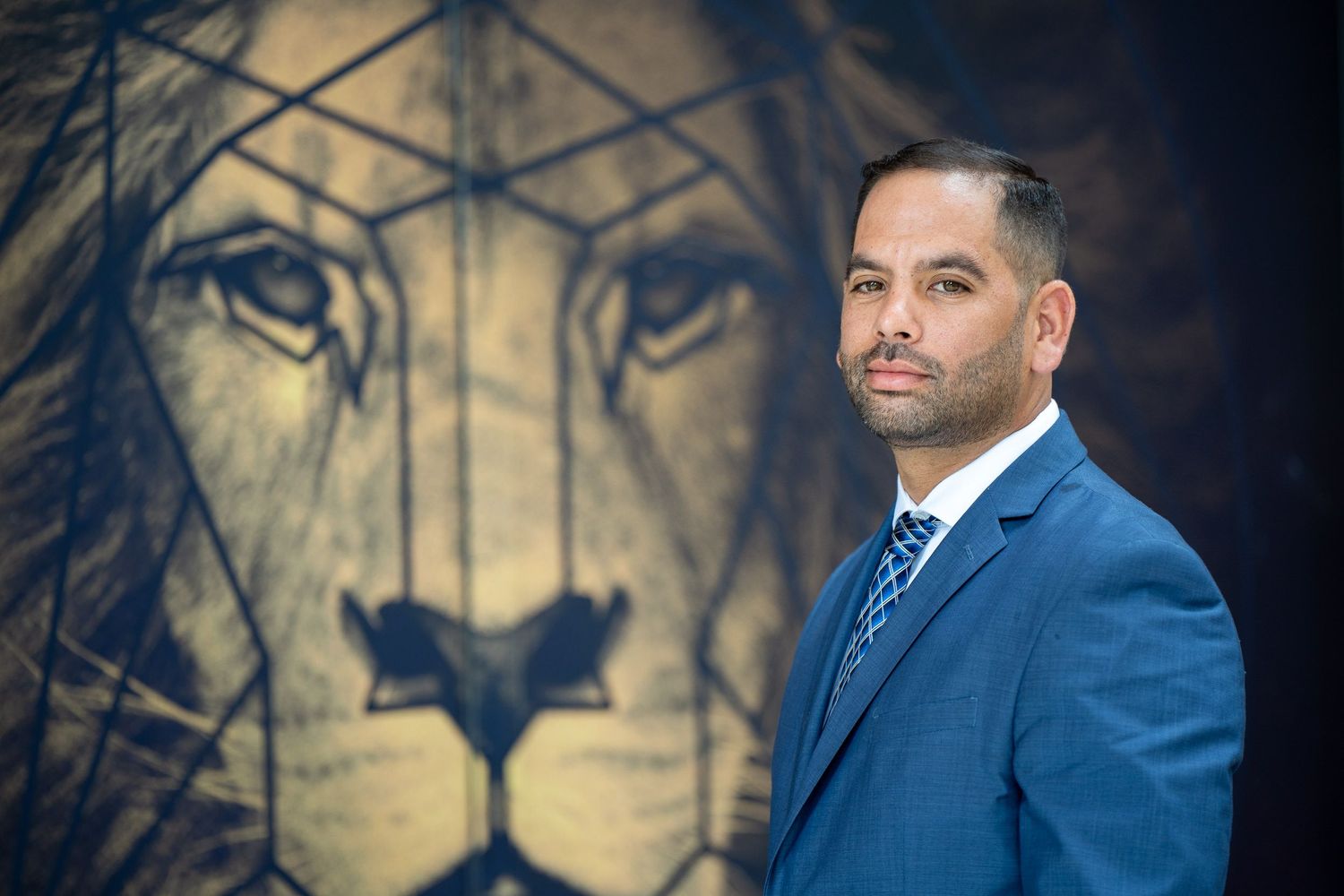 A business portrait in a suit and tie against a mural backdrop